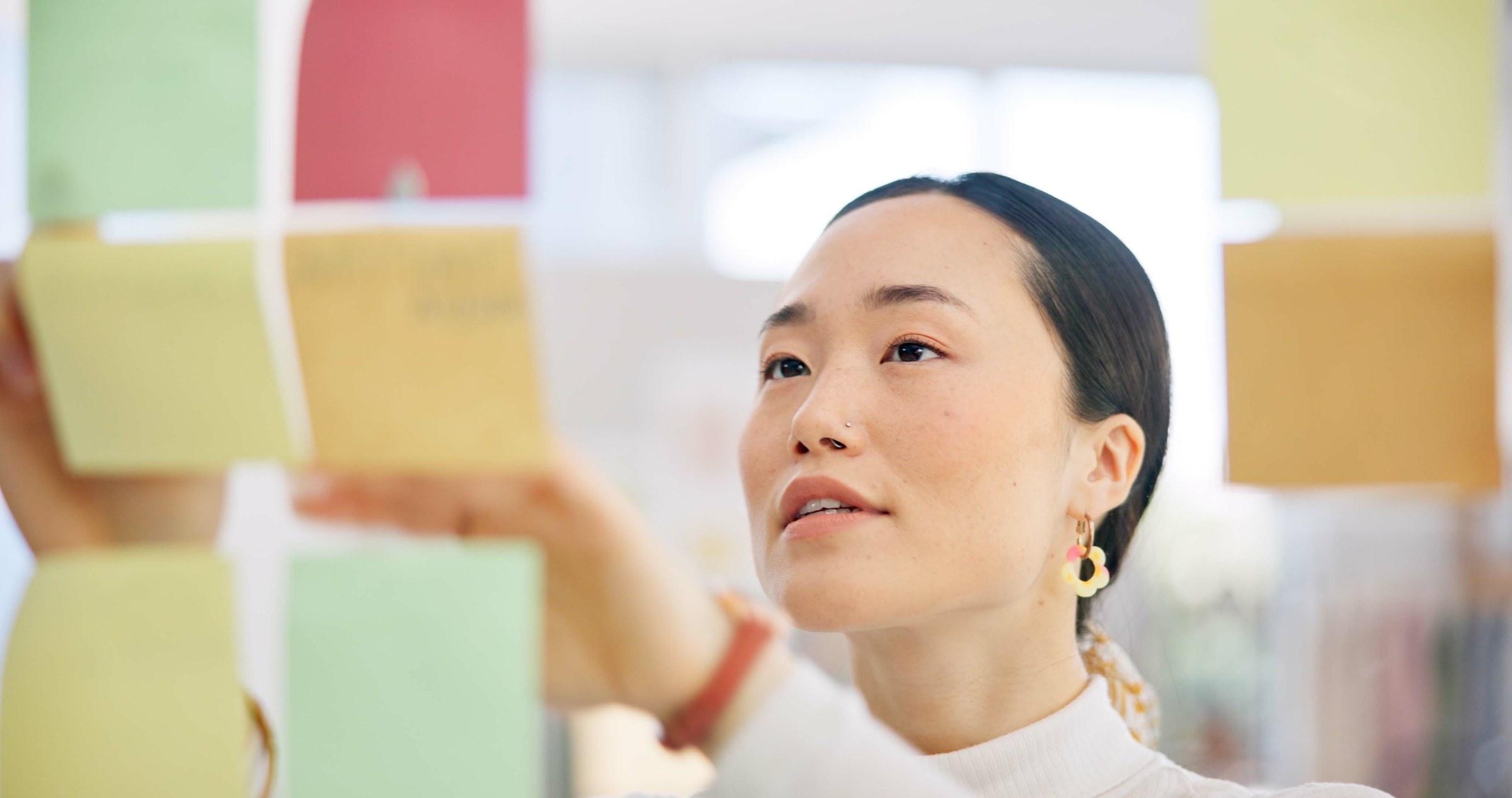 付箋を見上げながら、次のアイデアを考える女性